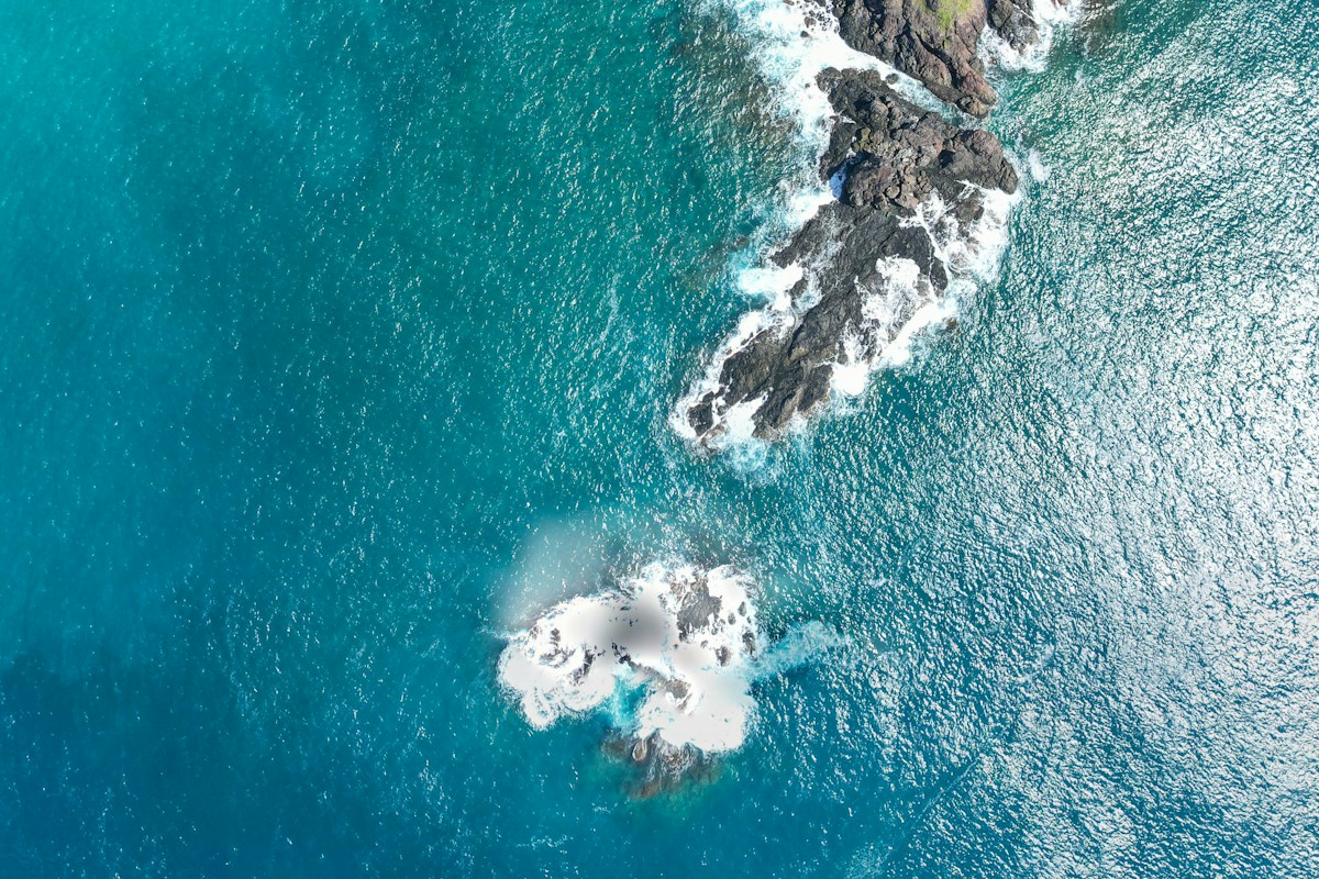 Aerial view of a rocky tropical coastline meeting turquoise and deep blue water