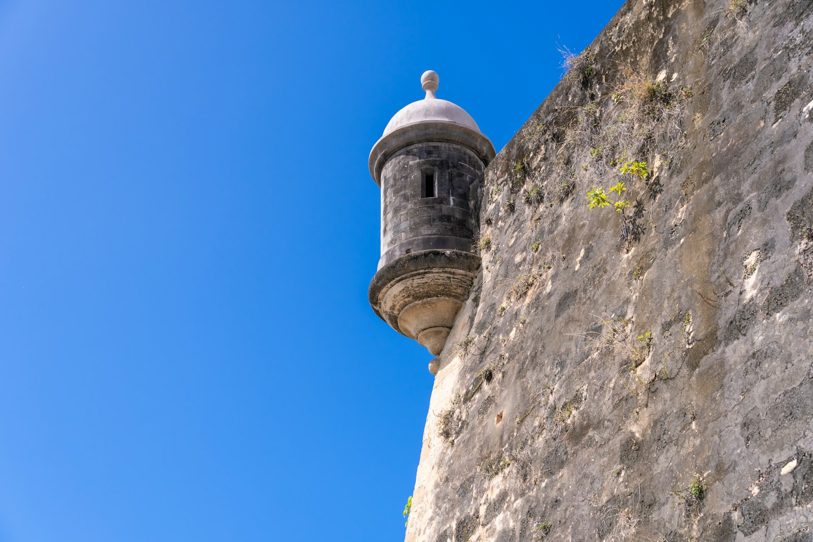 Stone sentry tower on the wall of El Morro fortress against a clear blue sky in San Juan, Puerto Rico